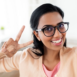 smiling woman taking selfie and showing v sign